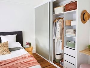 Organised wardrobe with hanging clothes and accessories.