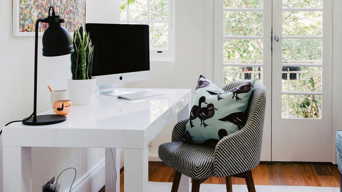 Home office with chair, desk, lamp, computer and French doors to garden