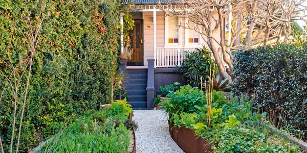 Pathway of stone to home with planter boxes laid out in yard