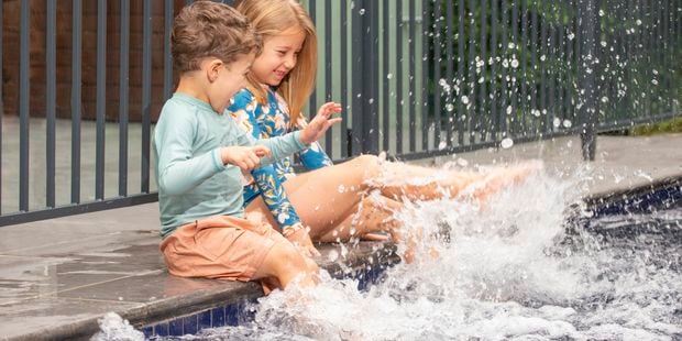 Two kids splashing their legs in a pool.