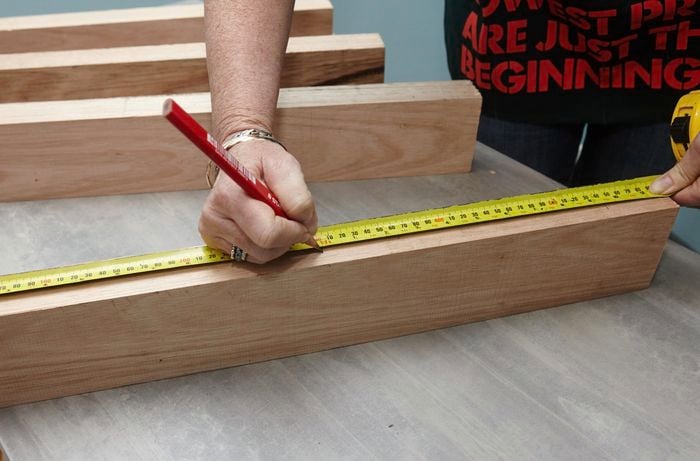 A person measuring and marking length on a piece of timber