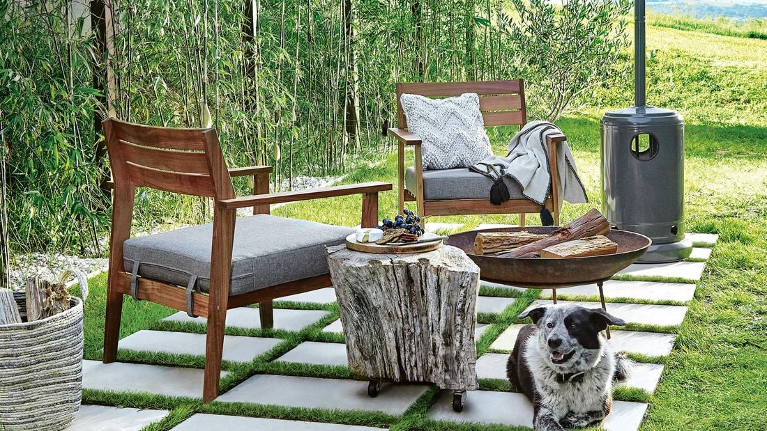 An outdoor seating area with a fire bit and a gas outdoor heater with a dog sitting in the foreground