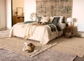Cosy bedroom featuring earth-toned furnishings and layered interior rugs.