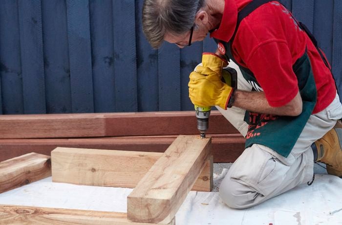 Framework for one end of a wooden outdoor day bed being screwed together