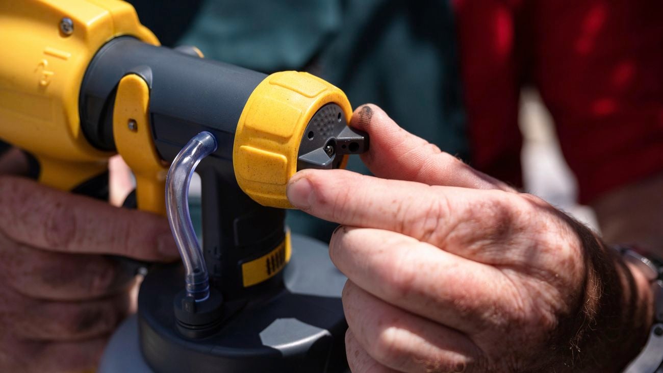 A Bunnings team member rotating the spray gun cap using his hand.