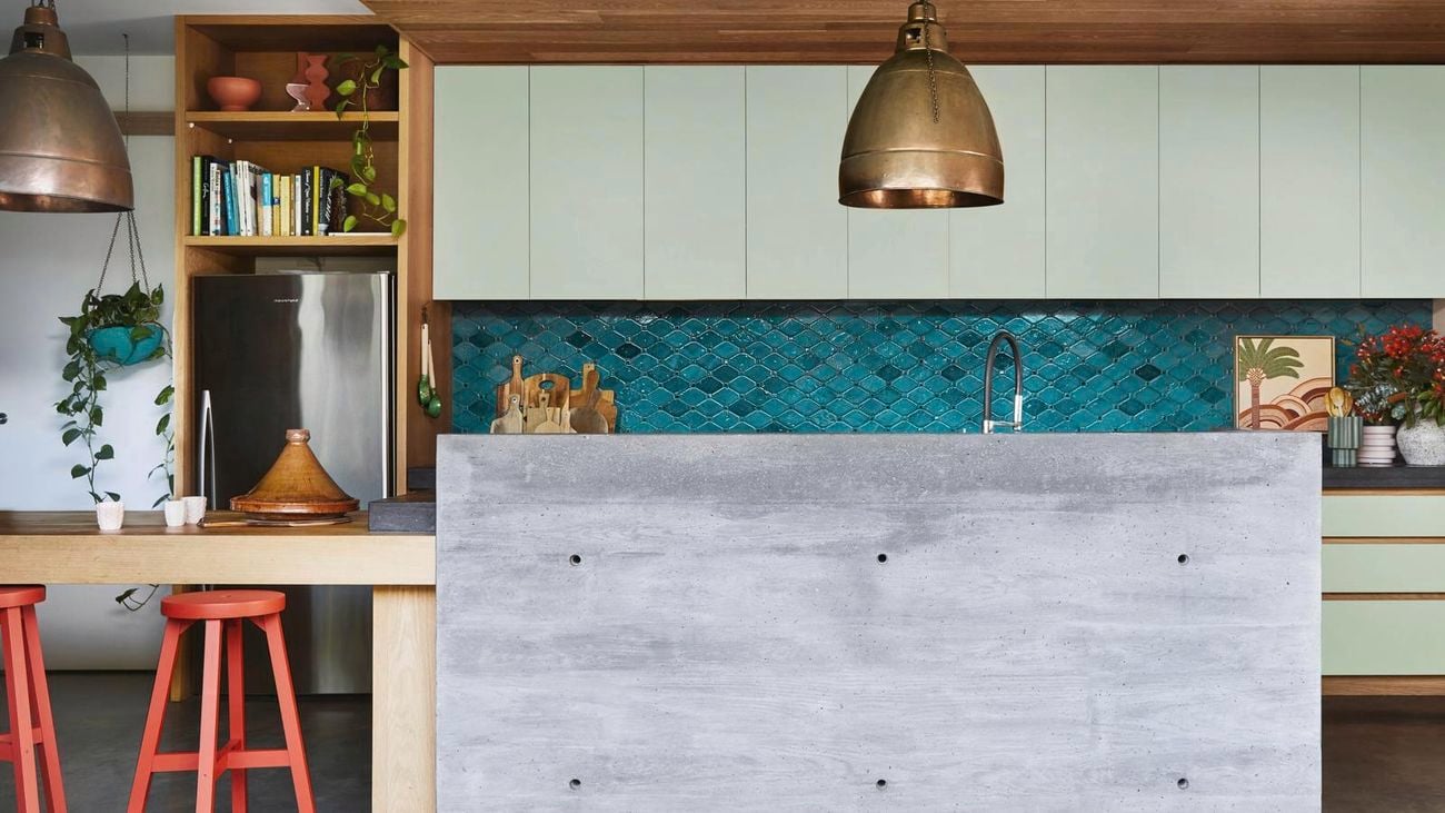 kitchen with blue tiled splashback, gold pendant lights and a concrete benchtop