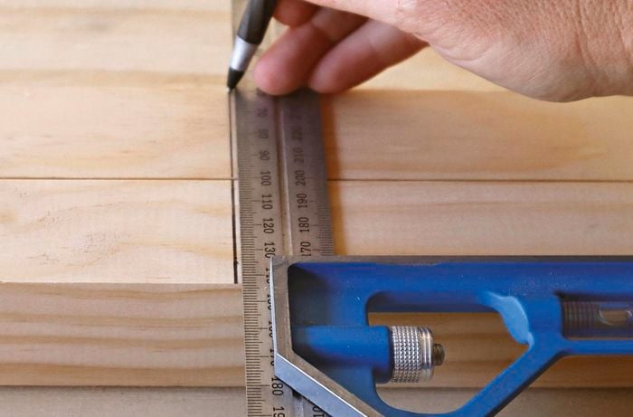 A square rule and pen being used to mark a piece of timber