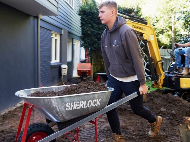 Tradesperson carting soil in wheelbarrow