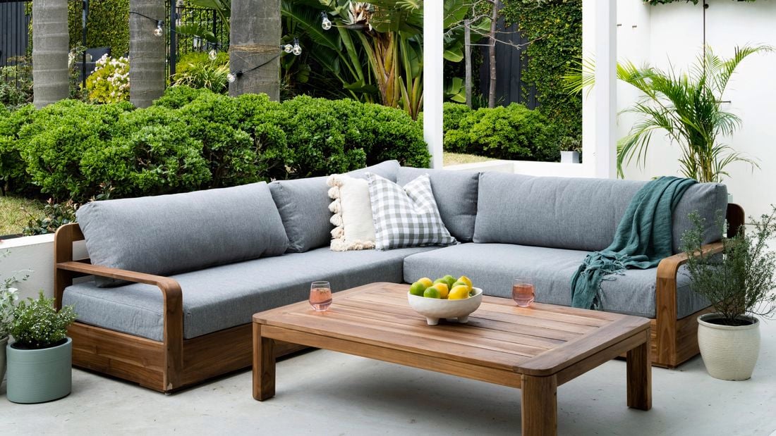 Timber and grey outdoor setting on a patio surrounded by greenery.
