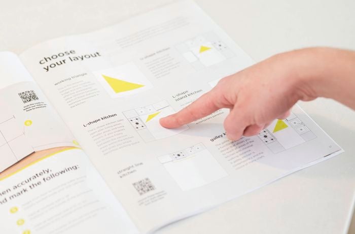 A person points to a kitchen layout diagram, highlighting different kitchen configurations and planning tips. 