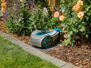 Gardena robotic lawnmower parked in a garden on its charging station