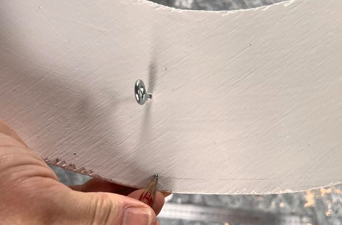 A person uses a pencil to mark a line on a white circle frame