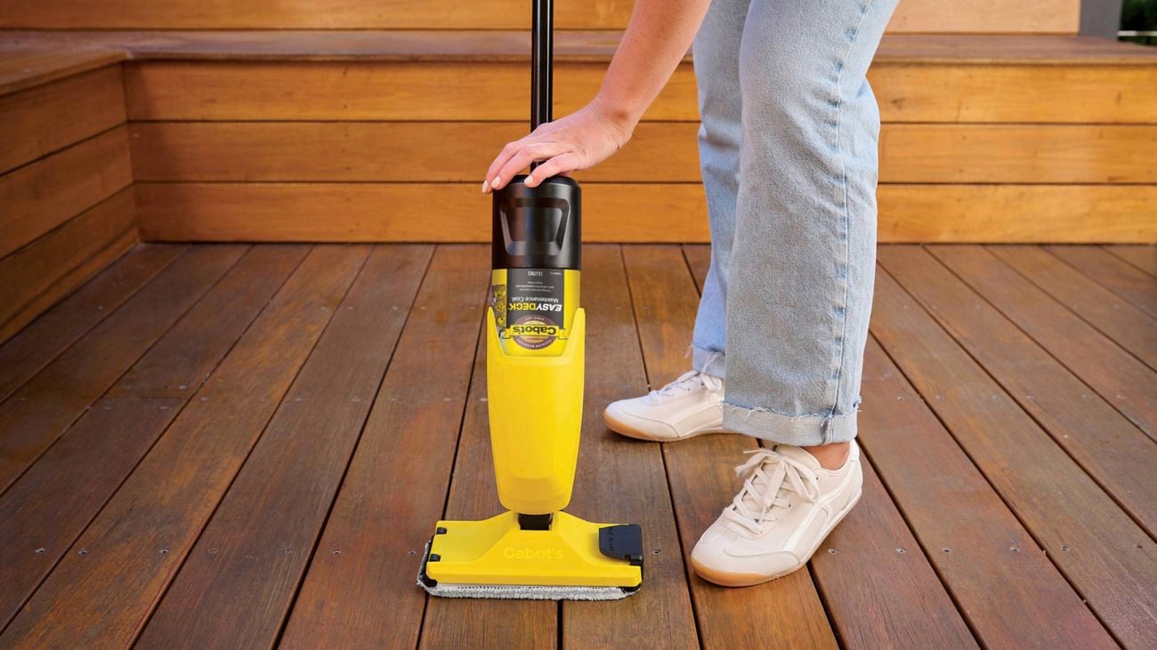 A woman’s legs and hand as she loads a bottle of Cabot’s Easy Deck Maintenance Coat into the Applicator