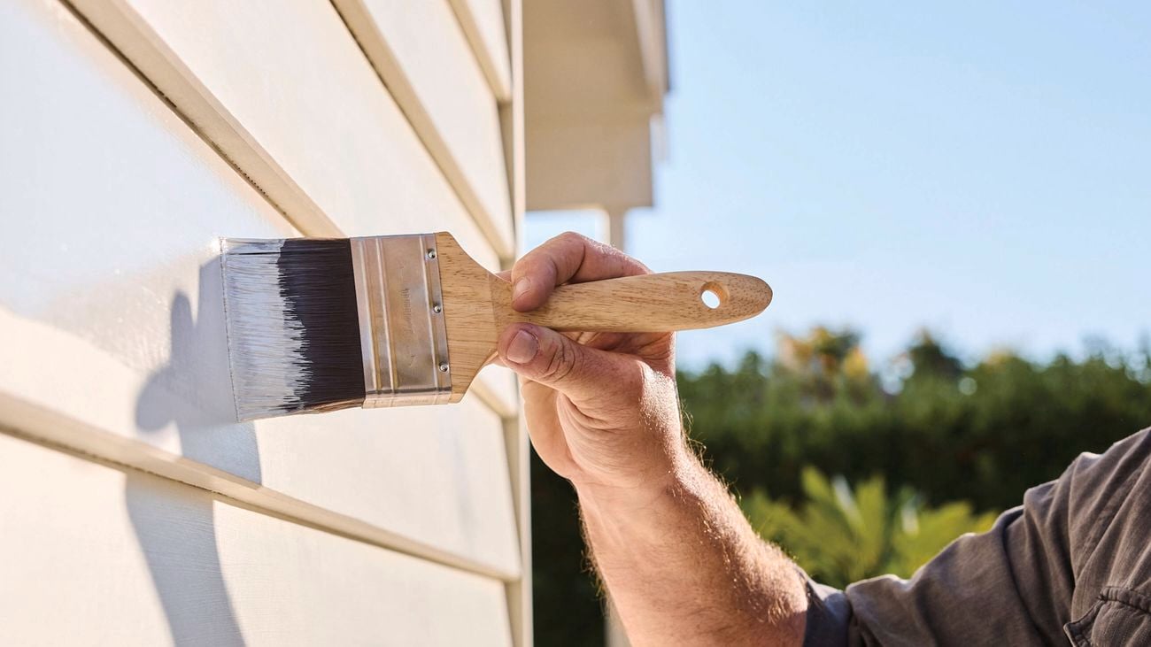 man painting the exterior of a timber house