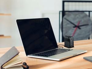 Laptop on a wooden desk with a charging hub aside