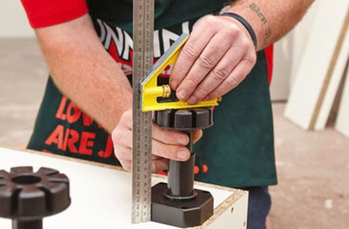 Legs being adjusted on an oven cabinet with a set square