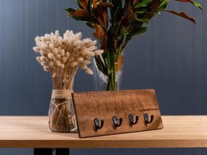 Table with 2 vases of flowers and a timber board with key hooks.