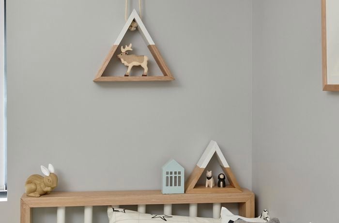 Wooden triangle shelves in a bedroom, one hanging from a rope