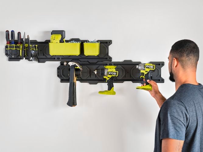A man hanging an impact driver onto a hook secured to a LINK wall plate.