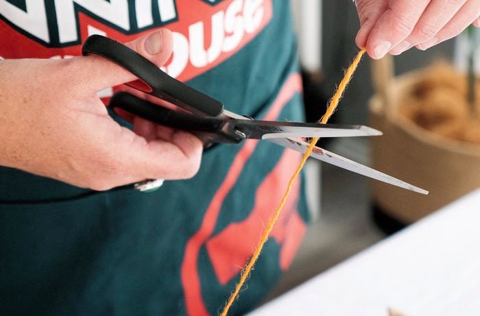 Scissors cutting orange string.