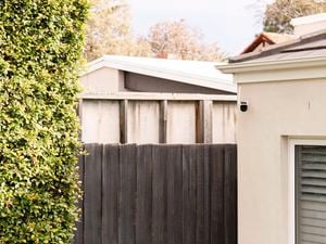 A Swann security camera is mounted on a house wall.