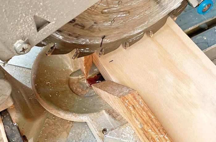 Close up perspective of mitre saw cutting a wooden rail