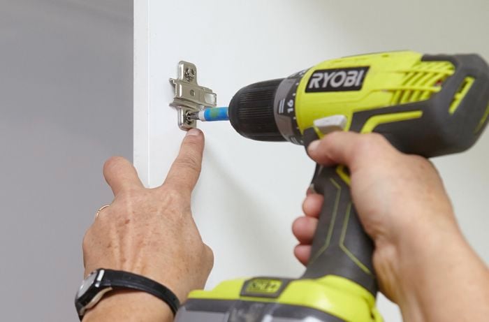 Person drilling into hinge.