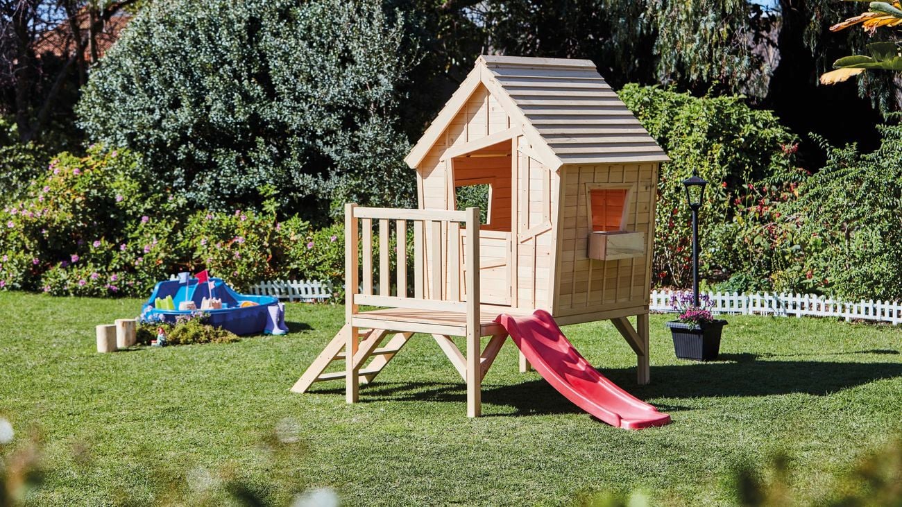 Naturally finished cubby house with red slide.
