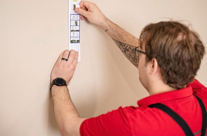 A Bunnings Team Member holding adhesive hook against a wall